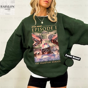 Op de afbeelding: Boszwarte sweatshirt met een Star Wars Episode I-afbeelding. Het ontwerp bevat beelden uit "The Phantom Menace" met een piloot en ruimtevaartuigen. De sweatshirt heeft een ronde hals en lange mouwen.