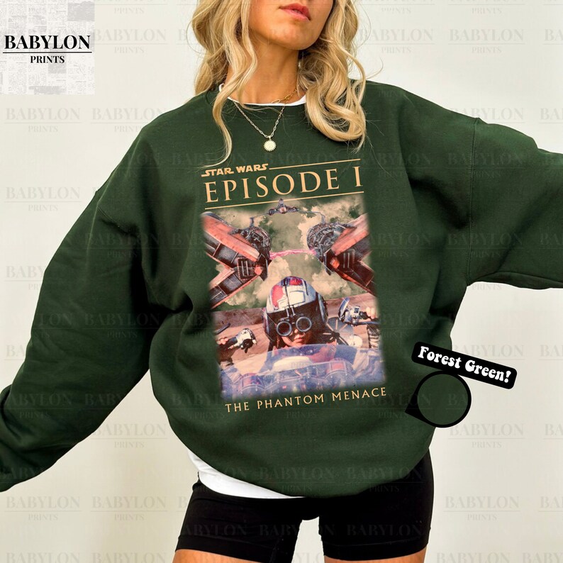 Op de afbeelding: Boszwarte sweatshirt met een Star Wars Episode I-afbeelding. Het ontwerp bevat beelden uit "The Phantom Menace" met een piloot en ruimtevaartuigen. De sweatshirt heeft een ronde hals en lange mouwen.