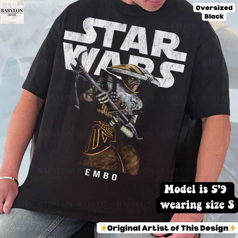 Puede incluir: Camiseta negra de gran tama&ntilde;o de Star Wars con un gr&aacute;fico detallado de Embo, un personaje del universo Star Wars, sosteniendo un arma. El logo de Star Wars es blanco. La camiseta es talla S.