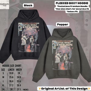 May include: Black and pepper-colored fleece boxy hoodies. Each hoodie features a Star Wars comic book cover design. The size chart shows measurements in inches. The hoodies are unisex.