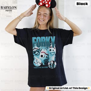 May include: Black t-shirt featuring the word "FORKY" in teal, with a graphic of Forky from Toy Story. The shirt also includes the text "I'M NOT A TOY. I'M A SPORK!" and the Babylon Prints logo.