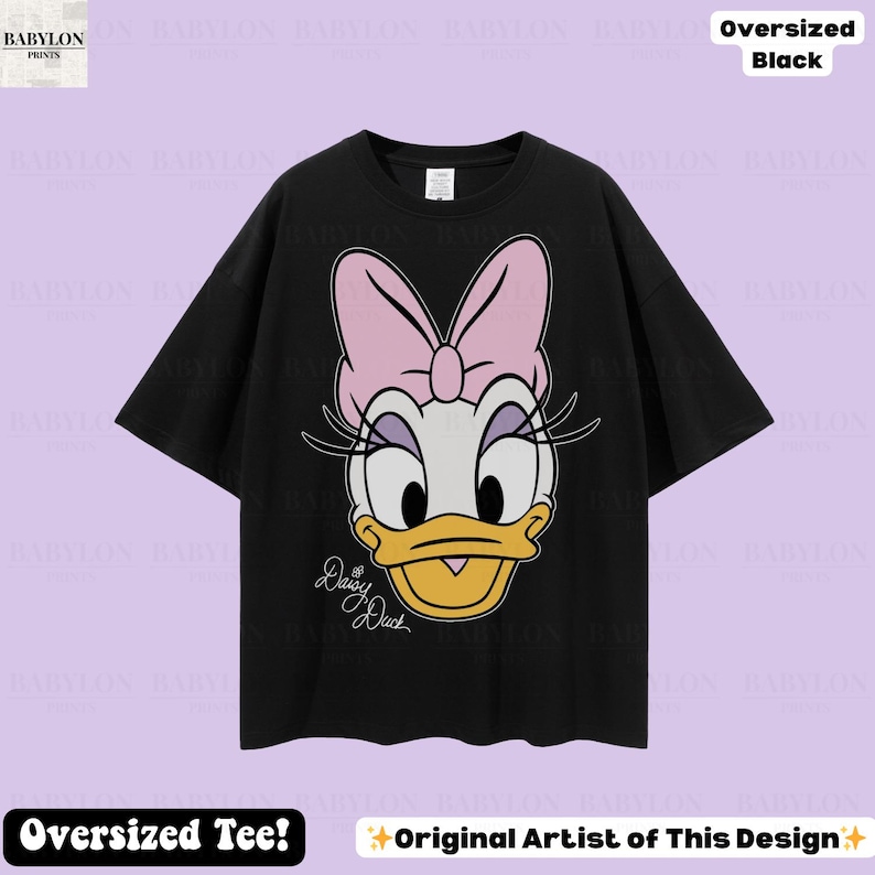 Puede incluir: Camiseta negra de gran tama&ntilde;o con un gran gr&aacute;fico de Daisy Duck, con un lazo rosa y pesta&ntilde;as. El texto "Daisy Duck" est&aacute; debajo de la imagen. La camiseta tiene el texto "Oversized Tee!" y "Original Artist of This Design" en la parte inferior.