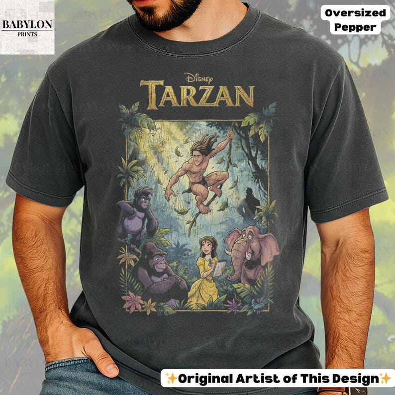 May include: Dark gray oversized t-shirt featuring a Disney Tarzan graphic. The design includes Tarzan swinging, gorillas, an elephant, and Jane. The shirt has the text "Disney Tarzan" across the top. The shirt is labeled "Oversized Pepper" and "Original Artist of This Design."