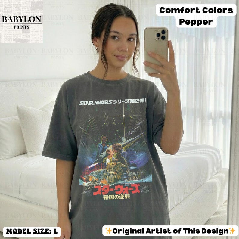May include: A dark gray t-shirt featuring a Star Wars movie poster design with Japanese text. The shirt has a crew neck and short sleeves. The text "STAR WARS" is visible at the top, with the Japanese title below the image. The model is wearing a size L.