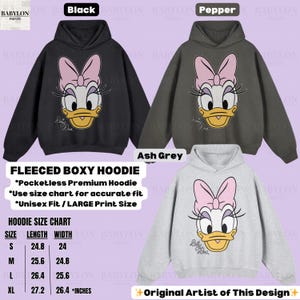 Puede incluir: Sudaderas con capucha boxy de forro polar negras, pimienta y gris ceniza con un gr&aacute;fico de Daisy Duck. Las sudaderas no tienen bolsillos y est&aacute;n disponibles en tallas unisex. La tabla de tallas muestra largos de 63 a 69 cm y anchos de 61 a 67 cm.