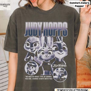 May include: Dark gray t-shirt featuring the text "JUDY HOPPS" in a gradient blue and white font, with images of the character Judy Hopps from the movie Zootopia. The shirt also includes the quote, "NO MATTER WHAT TYPE OF ANIMAL YOU ARE, CHANGE STARTS WITH YOU."