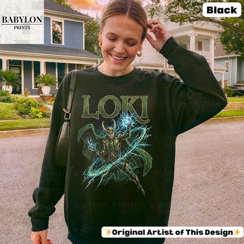 May include: Black sweatshirt featuring the word "LOKI" in green lettering above a graphic of the character. The graphic shows Loki with green cape and blue lightning. The sweatshirt is a crew neck style.