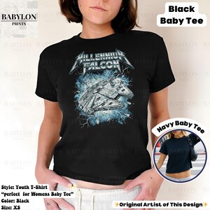 May include: Black youth t-shirt featuring a graphic of the Millennium Falcon spaceship with the text "Millennium Falcon" in a stylized font. The design includes blue lightning effects. The shirt is labeled as a "Baby Tee" and is size XS.