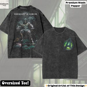 May include: A black oversized tee shirt with a distressed finish. The front features a green and silver Avengers logo. The back displays a graphic of a character with the text "DOOMSDAY IS COMING". The shirt is labeled "Premium Wash: Pepper".