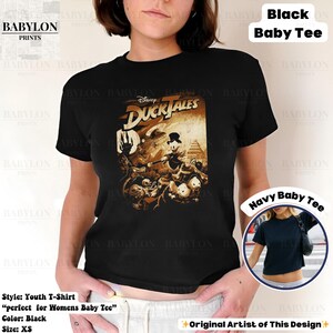 May include: Black youth t-shirt featuring a vintage-style graphic from Disney's DuckTales. The design showcases Scrooge McDuck and other characters in sepia tones. The shirt is a baby tee style and is size XS.