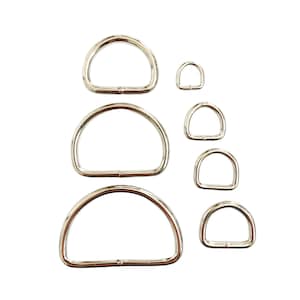 May include: A set of six silver metal D-rings of varying sizes. The rings are arranged in a vertical stack, with the largest ring at the top and the smallest ring at the bottom.