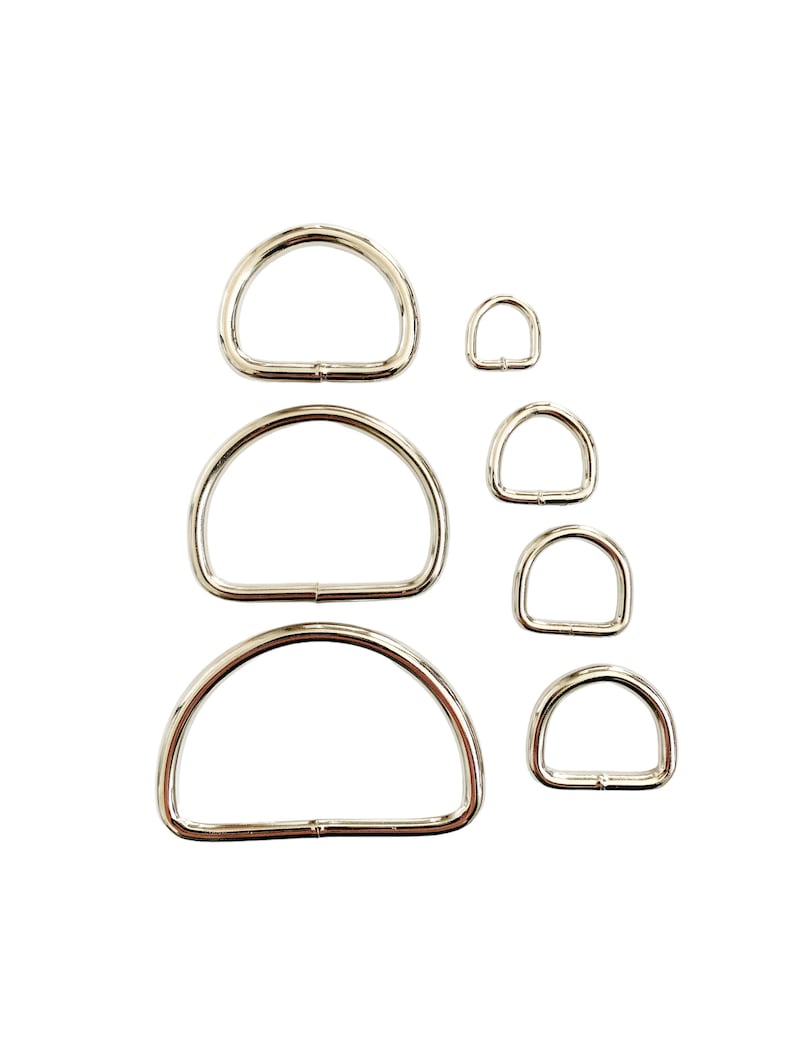 May include: A set of six silver metal D-rings of varying sizes. The rings are arranged in a vertical stack, with the largest ring at the top and the smallest ring at the bottom.