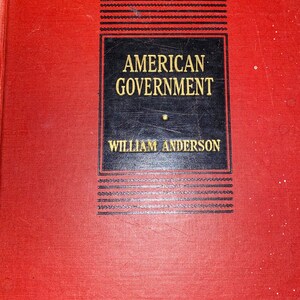 May include: A vintage hardcover book titled "AMERICAN GOVERNMENT" by William Anderson. The book has a red cover with the title and author in gold lettering on a black rectangular label.