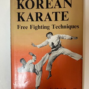 May include: Vintage book titled "KOREAN KARATE" with the subtitle "Free Fighting Techniques." The cover features two men in karate uniforms demonstrating fighting techniques against an orange and yellow gradient background. The author's name is "Sihak Henry Cho."