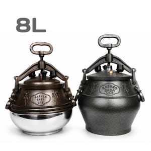May include: Two 8L pressure cookers with locking mechanisms and handles. The left cooker has a bronze-toned lid and a polished stainless steel base. The right cooker is entirely dark gray. Both feature floral engravings and the text RASHKO BABA LT.8.