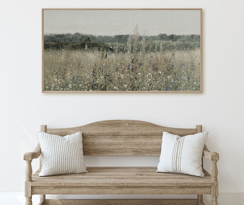 Puede incluir: Una pintura de paisaje enmarcada que representa un campo de flores silvestres en tonos de azul, blanco y verde. El fondo presenta una l&iacute;nea de &aacute;rboles en la distancia y un cielo nublado.