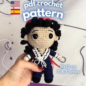 Puede incluir: Una muñeca de ganchillo con pelo negro rizado, cara beige y un conjunto azul marino con cuello de marinero blanco y corbata. La muñeca mide 18x12 cm. El texto en la imagen dice pdf crochet pattern e instant download.