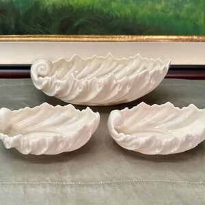 May include: A set of three ceramic mugs with a speckled, matte finish. The mugs are in shades of cream, light gray, and dark gray. Each mug has a simple, minimalist design and a rounded handle.