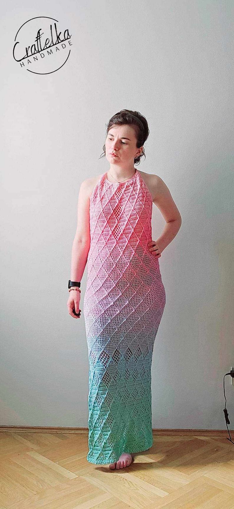 May include: A floor-length crochet dress featuring a halter neckline and a diamond-shaped openwork pattern. The garment displays a gradient color transition, shifting from a vibrant pink at the top to a soft blue and light green at the hem.