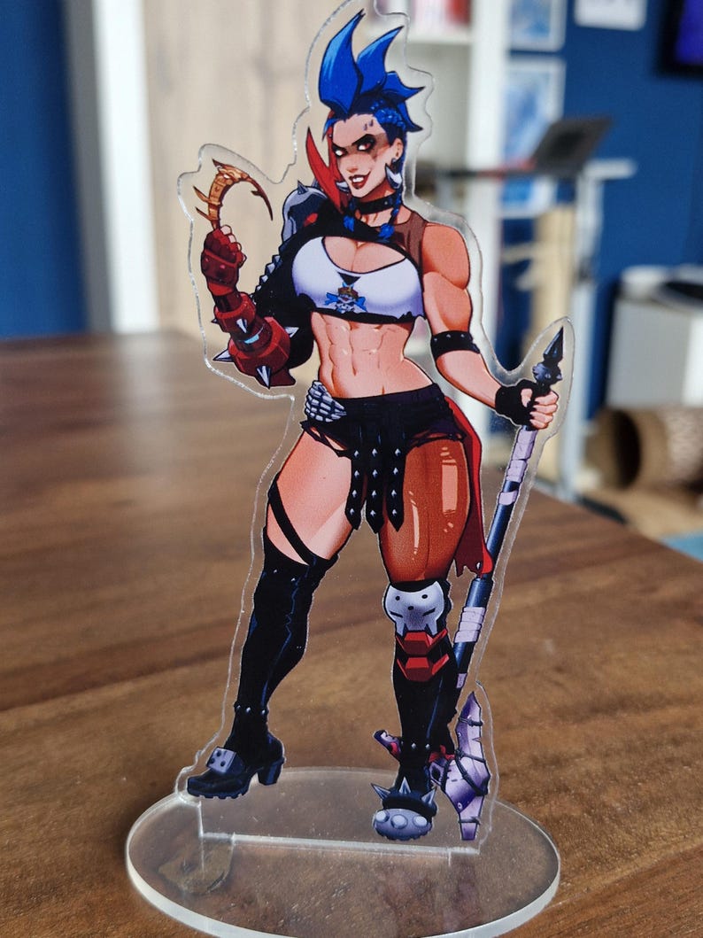 May include: A clear acrylic figure of a female character with blue hair, wearing a white and black top, black shorts, and knee-high boots. She is holding a weapon and has a determined expression. The figure is mounted on a clear circular base.