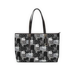 Peut inclure: Sac fourre-tout patchwork noir et blanc avec poignées et sangles noires. Le sac présente un motif répété de cachemire et de formes géométriques dans les tons de noir, blanc et gris. Le sac est de forme rectangulaire.