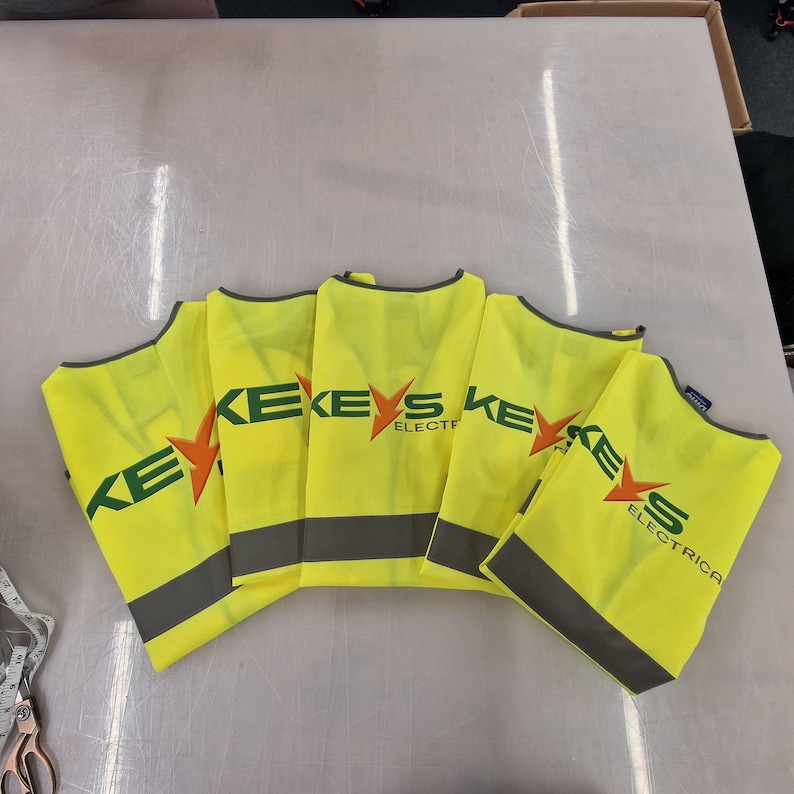 Puede incluir: Cinco chalecos de seguridad amarillos con rayas reflectantes negras y el texto "KEYS ELECTRICA" en verde y naranja.