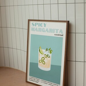 May include: A framed illustration of a spicy margarita cocktail recipe. The illustration features a glass of margarita with lime wedges, jalapeno slices, and ice. The text reads "Spicy Margarita Cocktail" and includes the ingredients: 3 ounces tequila, 2 ounces orange liqueur, 1 ounce lime juice, 1/2 ounce agave syrup, and jalapeno coins.
