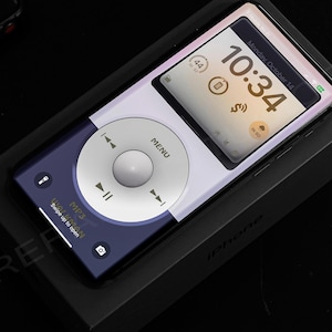 May include: A white and blue smartphone with a custom iPod Classic-style user interface. The screen displays the time, "10:34", and the date, "Monday, October 14". The phone is in a black box with the word "iPhone" printed on it.