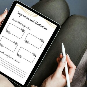 May include: A digital tablet with a white background and black text that reads "Inspiration and Motivation". The tablet has a gold design and four blank boxes with black floral designs. The text "Quotes That Inspire Me" is above the boxes. Below the boxes is the text "Personal Manifesto or Motto".
