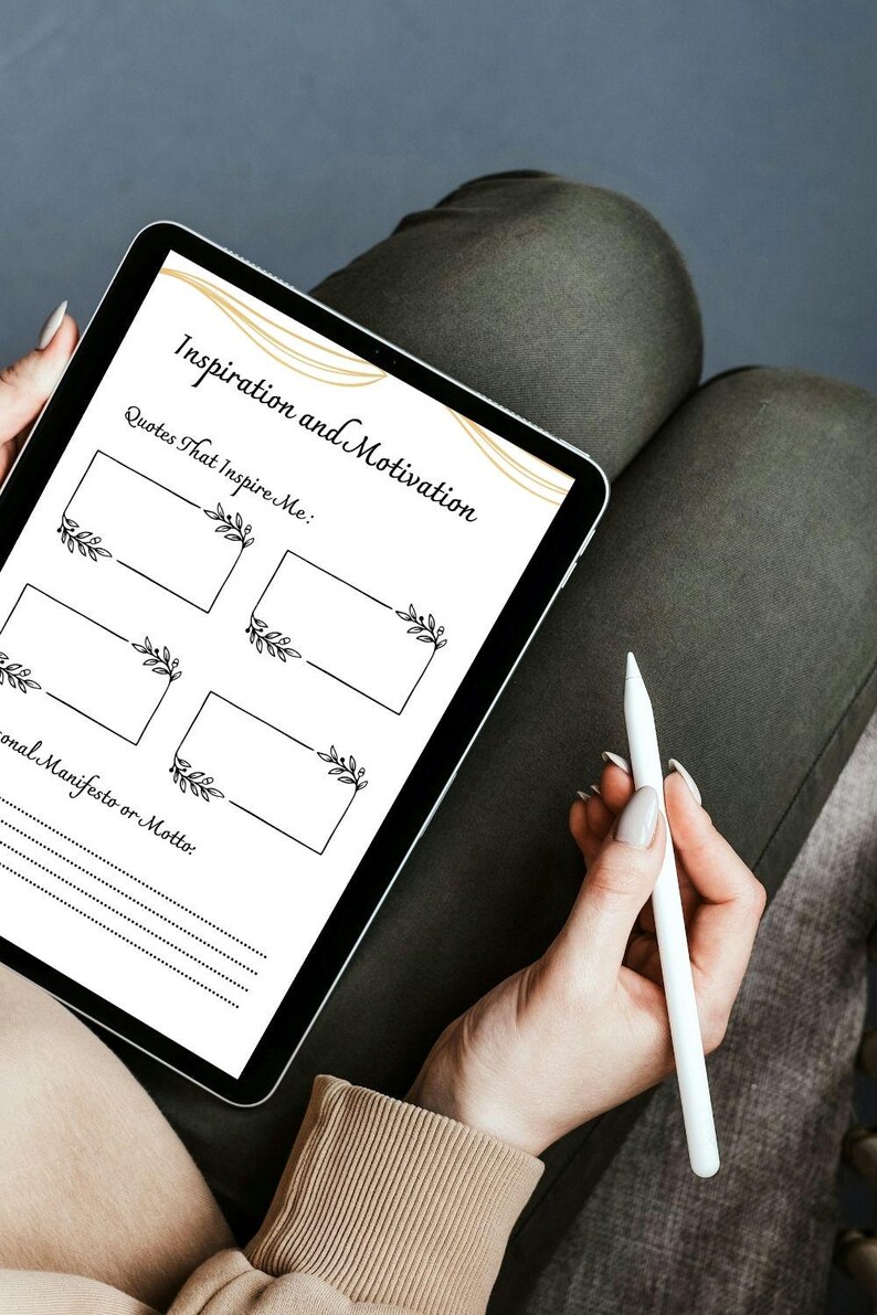 May include: A digital tablet with a white background and black text that reads "Inspiration and Motivation". The tablet has a gold design and four blank boxes with black floral designs. The text "Quotes That Inspire Me" is above the boxes. Below the boxes is the text "Personal Manifesto or Motto".
