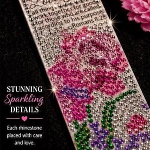 Puede incluir: Un marcapáginas blanco adornado con brillantes pedrería en tonos rosa, morado y verde, formando un diseño floral. El marcapáginas presenta el texto "Love You" y un versículo bíblico. También se ven las palabras "Stunning Sparkling Details".