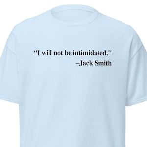 May include: A light blue t-shirt with the quote "I will not be intimidated." attributed to Jack Smith in black text. The shirt has short sleeves and a crew neck.