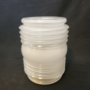 May include: A white frosted glass lampshade with a ribbed design. The lampshade is cylindrical and has a smooth, opaque finish.