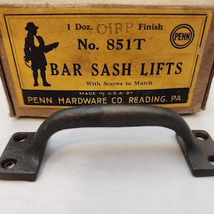 May include: A black metal bar sash lift with a rounded handle and two screw holes on each side. The box reads "1 Doz. OIRP Finish No. 851T BAR SASH LIFTS With Screws to Match MADE IN USA BY PENN HARDWARE CO. READING. PA".