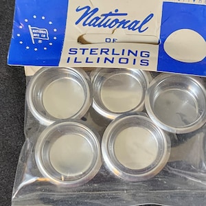 May include: A package of six silver-colored metal drawer pulls. The package is labeled "National of Sterling Illinois".