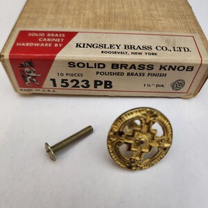 May include: A gold-toned brass cabinet knob with a decorative design. The knob is 1 1/2 inches in diameter and comes with a screw. The box reads "Solid Brass Knob, 10 Pieces, Polished Brass Finish, 1523 PB, 1 1/2" Dia., Made in U.S.A."