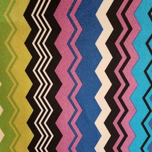 May include: A colorful fabric with a chevron pattern in shades of green, black, pink, blue, white, and turquoise.