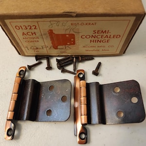 May include: Antique copper semi-concealed hinges with mounting screws, displayed with the original packaging. The box reads "RIST-O-KRAT" and "ACORN MFG. CO."