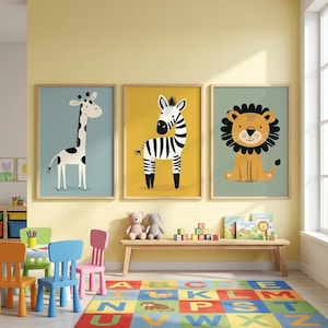 Op de afbeelding: Drie ingelijste dierenkunstprints: een giraffe met zwarte vlekken op een lichtblauwe achtergrond, een zebra op een gele achtergrond en een leeuw op een groene achtergrond. De prints bevinden zich in een kinderspeelkamer met kleurrijk meubilair en een vloerkleed.