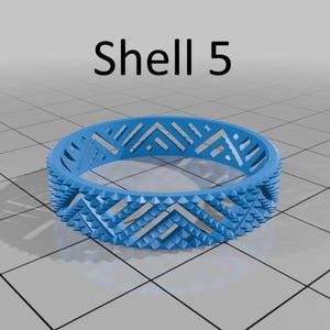 May include: A light blue ring with a geometric design. The ring has a repeating chevron pattern and small, pointed details around the edges. The text "Shell 5" is above the ring.