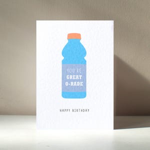 Puede incluir: Una tarjeta blanca con una ilustración de una botella de agua azul y el texto "You're Great O-Rade" y "Happy Birthday".