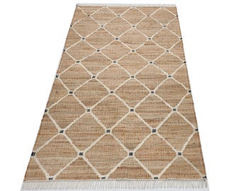 May include: A rectangular, woven jute rug with a diamond pattern. The rug features a natural tan color with a white diamond grid and small black squares at the intersections. The rug has a fringe on the short end.