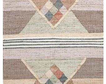 May include: A woven rug with a geometric design. The rug features triangles and diamond shapes in shades of beige, brown, green, and gray. Horizontal stripes in black and white are at the top and bottom. The rug has a fringed edge.