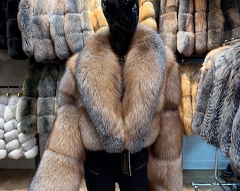 Könnte beinhalten: Eine kurz geschnittene Jacke aus dickem, langhaarigem braunem und grauem Fell mit einem breiten, voluminösen Schalkragen. Die Jacke hat lange Ärmel und wird auf einem schwarzen Schaufensterpuppen-Torso präsentiert, mit einem kleinen Markenetikett.
