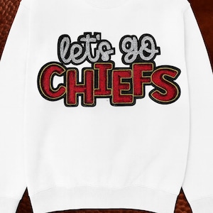 May include: White sweatshirt with the text "let's go CHIEFS" in a bold, eye-catching design. The text is in red and black with gold accents, perfect for showing team spirit. The sweatshirt is a comfortable, casual style.