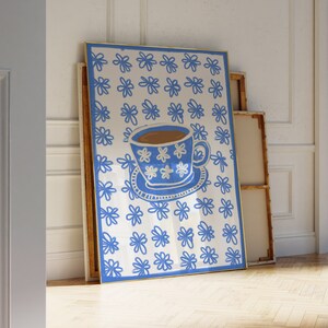 May include: A blue and white coffee cup with a floral pattern on a white background with blue floral designs. The cup is filled with coffee and has a white saucer.