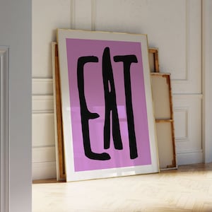 Peut inclure: Une impression encadrée avec un fond rose et le mot "EAT" écrit en noir.