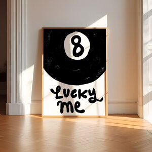 May include: A black and white poster with a black 8-ball and the text "Lucky Me" in a white cursive font.