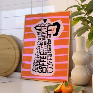 May include: A framed print with an orange and pink striped background featuring a black and white illustration of a coffee pot with the word "COFFEE" repeated throughout the design.