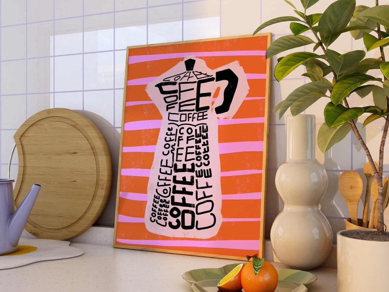 May include: A framed print with an orange and pink striped background featuring a black and white illustration of a coffee pot with the word "COFFEE" repeated throughout the design.
